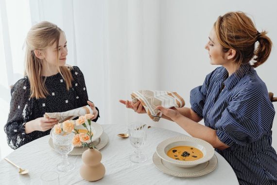 A mother and daughter share a meal, focusing on table etiquette and bonding over lunch.